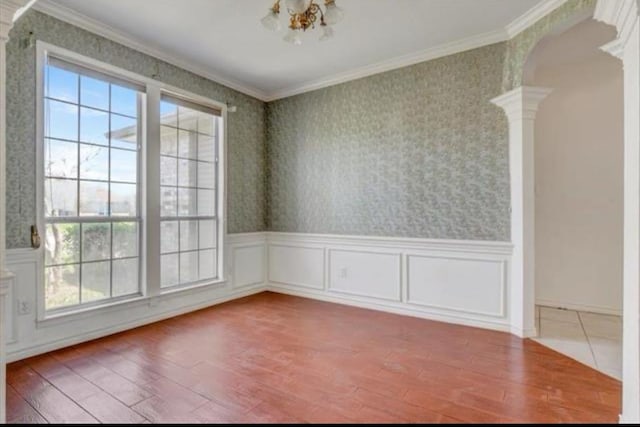 spare room with ornamental molding, a healthy amount of sunlight, decorative columns, and wallpapered walls