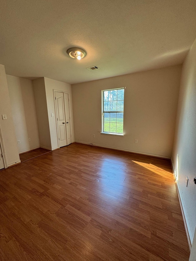 spare room with a textured ceiling and hardwood / wood-style flooring