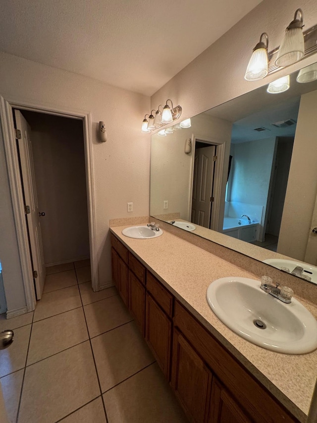 bathroom with tile patterned floors, a tub to relax in, and vanity