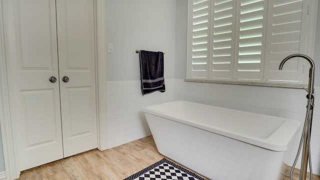 5065 Turner Rd, Orange, TX 77630 - bathroom featuring a freestanding bath, a wainscoted wall, wood finished floors, and tile walls