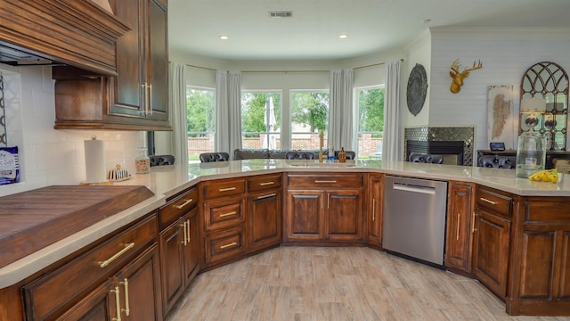 5065 Turner Rd, Orange, TX 77630 - kitchen featuring dishwasher, a tiled fireplace, light countertops, decorative backsplash, and light wood-style flooring