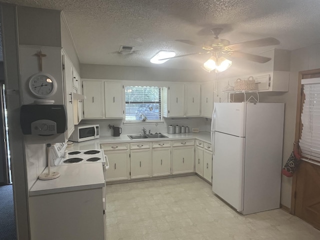 kitchen with white appliances, sink, ceiling fan, a textured ceiling, and white cabinetry