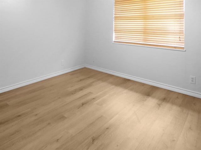 unfurnished room featuring wood finished floors, a healthy amount of sunlight, and baseboards
