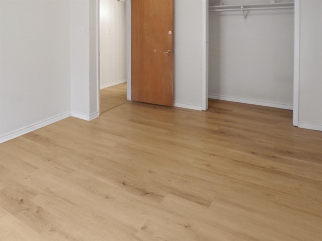 unfurnished bedroom with baseboards, a closet, and light wood-style flooring