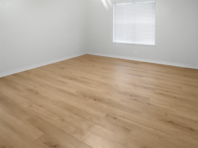 empty room with baseboards and light wood-style flooring
