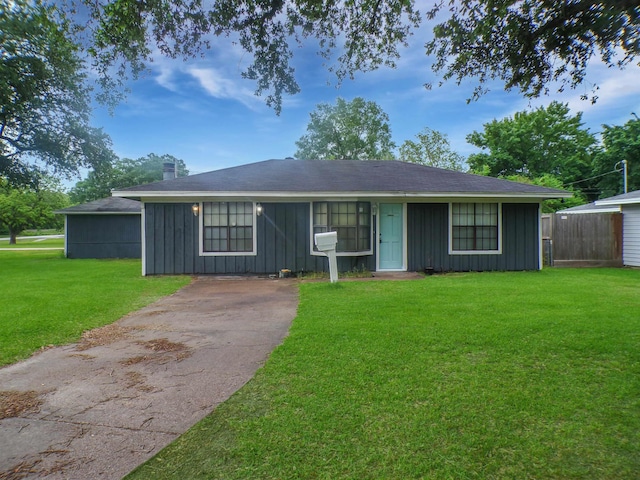 view of front of home with board and batten siding, a front lawn, and fence