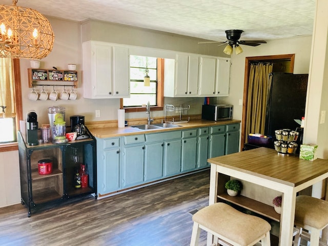 kitchen featuring black fridge, ceiling fan, pendant lighting, white cabinets, and dark hardwood / wood-style floors