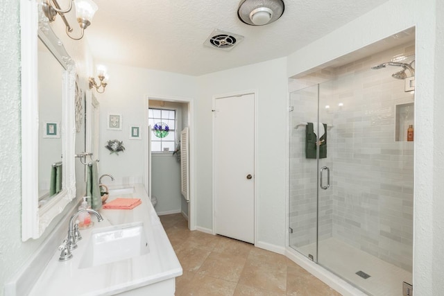 bathroom with a shower with shower door, a textured ceiling, vanity, and tile patterned flooring