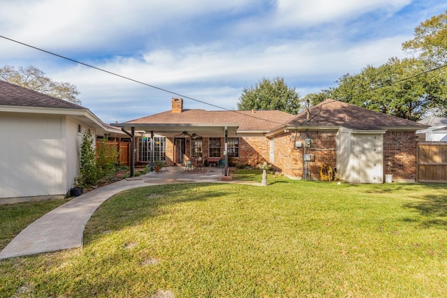 rear view of property with ceiling fan, a patio area, and a lawn