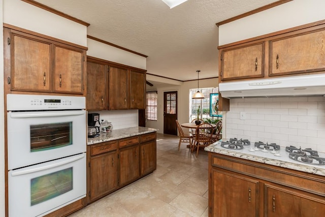 kitchen with decorative light fixtures, backsplash, crown molding, white appliances, and a textured ceiling