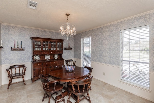 dining room with a textured ceiling, an inviting chandelier, ornamental molding, and plenty of natural light