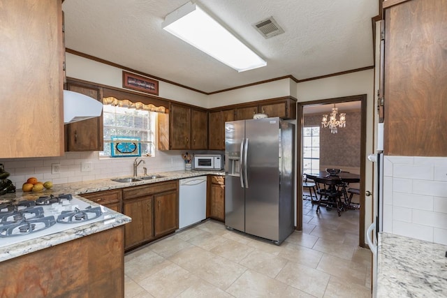 kitchen with white appliances, a wealth of natural light, sink, hanging light fixtures, and a notable chandelier