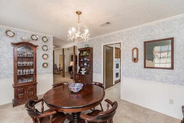 tiled dining space featuring a textured ceiling, ornamental molding, and a chandelier