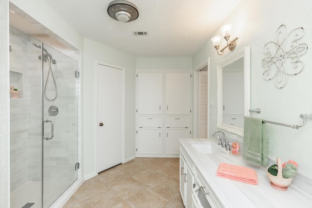 bathroom featuring a textured ceiling, a shower with door, and vanity