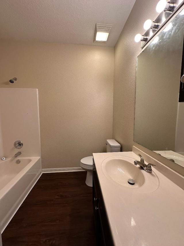 full bathroom with bathing tub / shower combination, hardwood / wood-style floors, a textured ceiling, toilet, and vanity