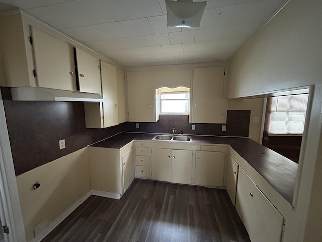 kitchen with dark countertops, a sink, dark wood finished floors, and white cabinets