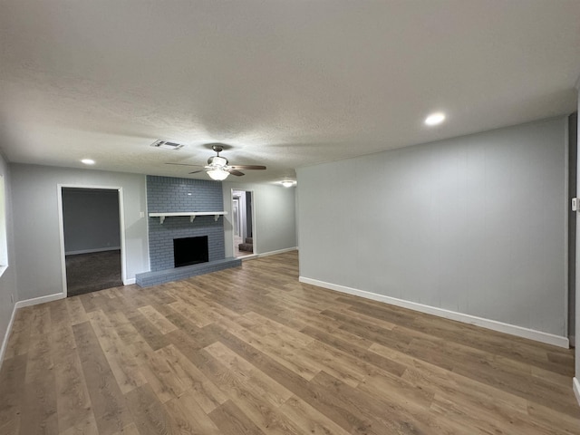 unfurnished living room with hardwood / wood-style floors, ceiling fan, a fireplace, and a textured ceiling