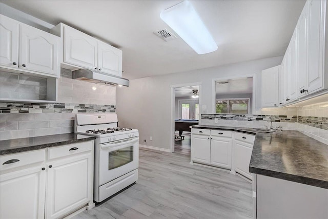2125 10th St, Port Neches, TX 77651 - kitchen with white gas range oven, a sink, tasteful backsplash, and under cabinet range hood