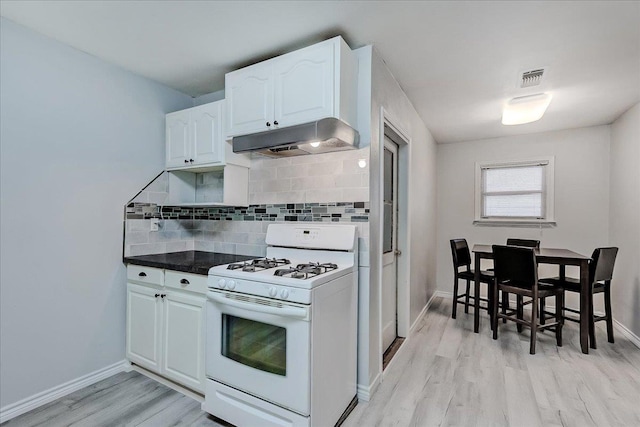 2125 10th St, Port Neches, TX 77651 - kitchen with white range with gas cooktop, under cabinet range hood, light wood-type flooring, tasteful backsplash, and white cabinetry