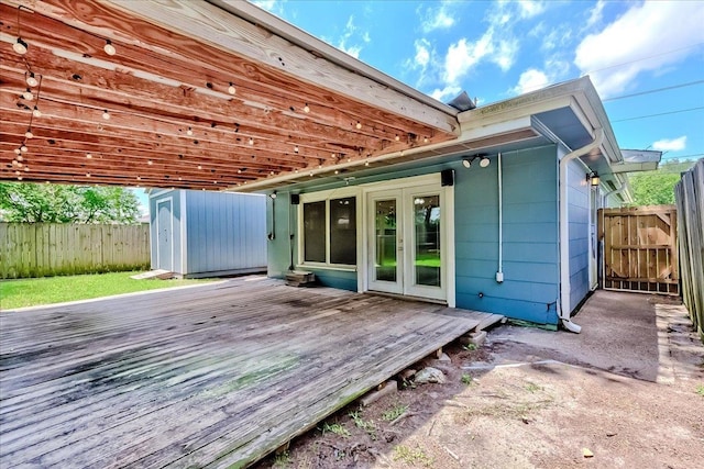 2125 10th St, Port Neches, TX 77651 - back of property featuring french doors, a wooden deck, a fenced backyard, a storage unit, and an outbuilding