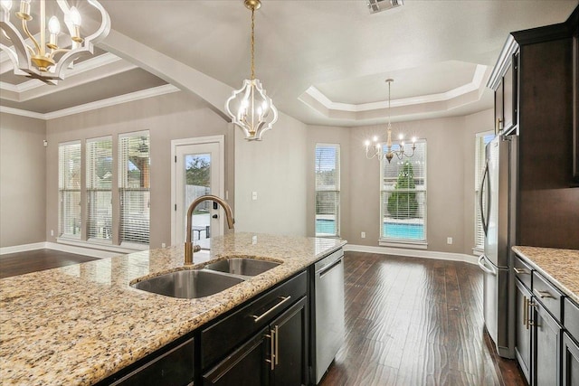 kitchen with light stone countertops, appliances with stainless steel finishes, a raised ceiling, crown molding, and sink