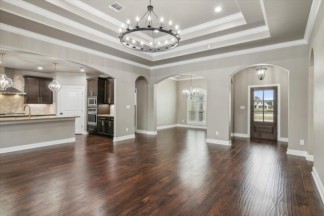 unfurnished living room featuring dark hardwood / wood-style flooring, a raised ceiling, ornamental molding, and sink