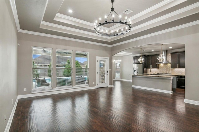 unfurnished living room featuring sink, dark hardwood / wood-style flooring, crown molding, and a tray ceiling