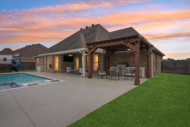 view of pool with a pergola, a patio area, a lawn, and an outdoor kitchen