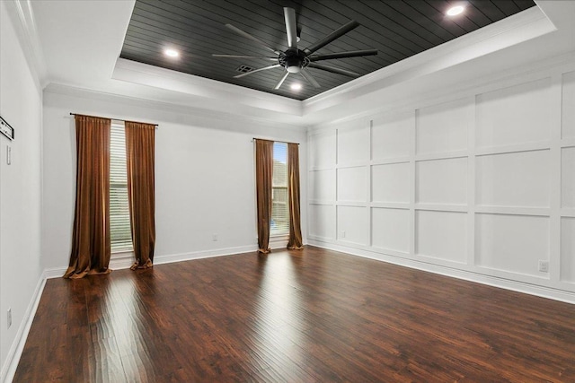 unfurnished room featuring a raised ceiling, ceiling fan, dark wood-type flooring, and ornamental molding