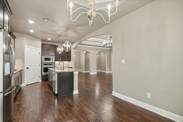 kitchen featuring sink, an island with sink, decorative backsplash, dark brown cabinets, and appliances with stainless steel finishes