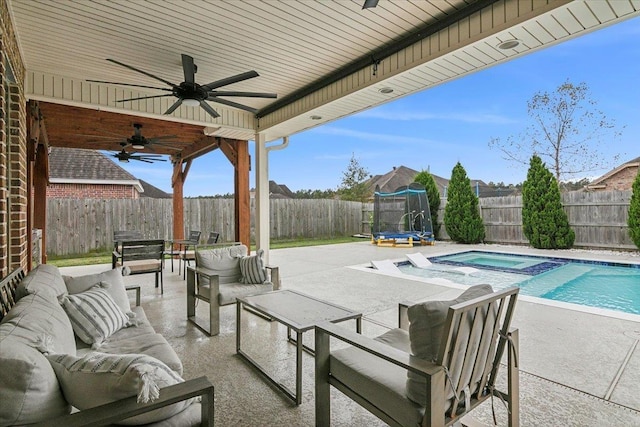 view of patio with ceiling fan, a pool with hot tub, an outdoor hangout area, and a trampoline