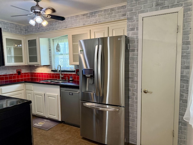 kitchen featuring a sink, dark countertops, appliances with stainless steel finishes, brick wall, and ceiling fan