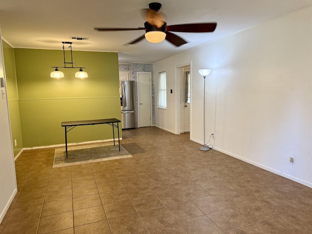 spare room featuring ornamental molding, baseboards, visible vents, and ceiling fan