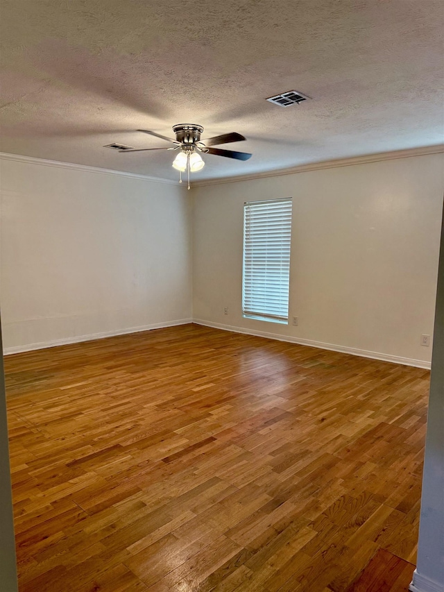 empty room featuring visible vents, ornamental molding, and wood finished floors