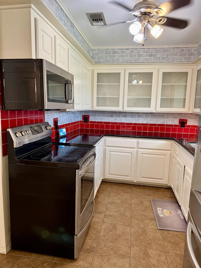 kitchen with tasteful backsplash, visible vents, dark countertops, light tile patterned floors, and stainless steel appliances