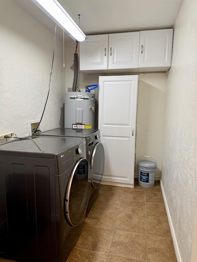 laundry area featuring light tile patterned flooring, cabinet space, electric water heater, a textured wall, and independent washer and dryer