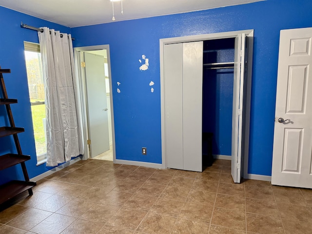 unfurnished bedroom featuring multiple windows, baseboards, and a closet