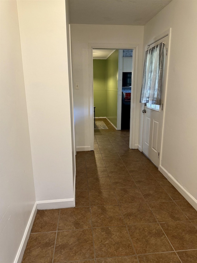 hallway featuring dark tile patterned flooring and baseboards