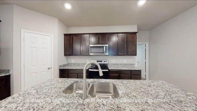 1690 Haidlyns Way, Sour Lake, TX 77659 - kitchen with appliances with stainless steel finishes, a sink, dark brown cabinetry, recessed lighting, and light stone counters