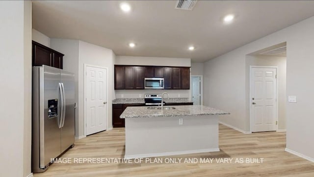 1690 Haidlyns Way, Sour Lake, TX 77659 - kitchen with appliances with stainless steel finishes, a sink, light wood-style flooring, an island with sink, and dark brown cabinets
