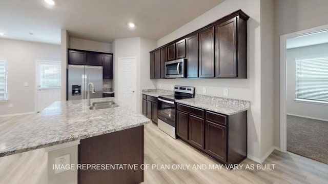 1690 Haidlyns Way, Sour Lake, TX 77659 - kitchen with appliances with stainless steel finishes, dark brown cabinets, light wood-style floors, a sink, and baseboards