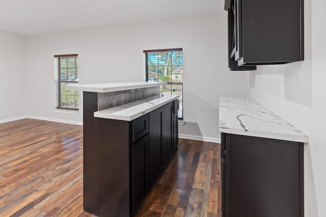 kitchen with dark wood-type flooring, a wealth of natural light, and a breakfast bar area