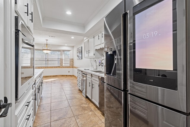 kitchen with appliances with stainless steel finishes, sink, light tile patterned floors, white cabinetry, and hanging light fixtures