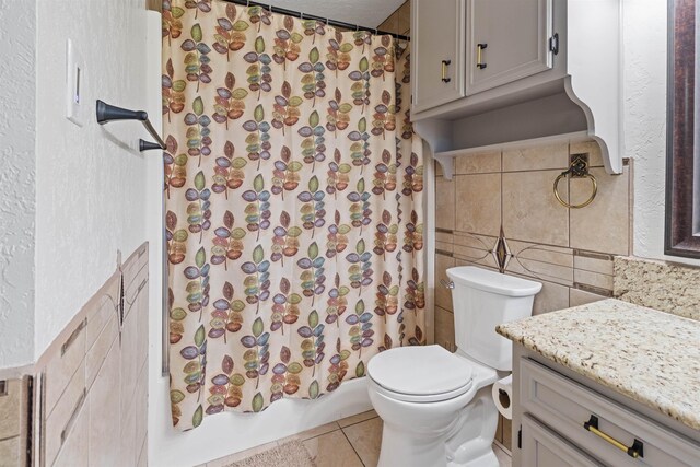 full bathroom with vanity, shower / bath combo, tile patterned floors, toilet, and tile walls