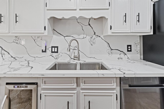 kitchen featuring light stone countertops, sink, white cabinets, and beverage cooler