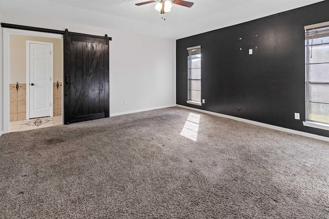 spare room with a barn door, light carpet, plenty of natural light, and ceiling fan