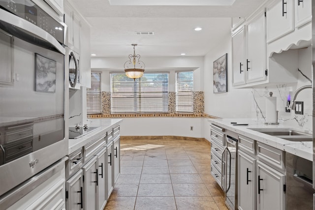 kitchen with sink, hanging light fixtures, black electric cooktop, decorative backsplash, and white cabinets