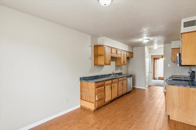 kitchen with sink, stainless steel appliances, a textured ceiling, and light wood-type flooring