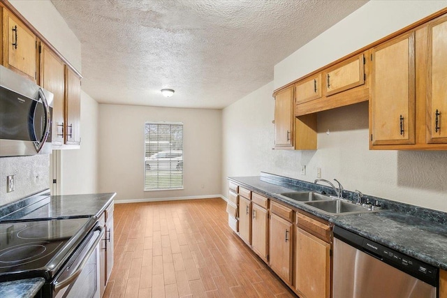 kitchen featuring stainless steel appliances, light hardwood / wood-style floors, sink, and a textured ceiling