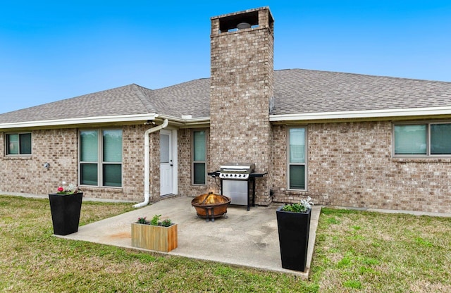 rear view of house with a yard, an outdoor fire pit, and a patio area